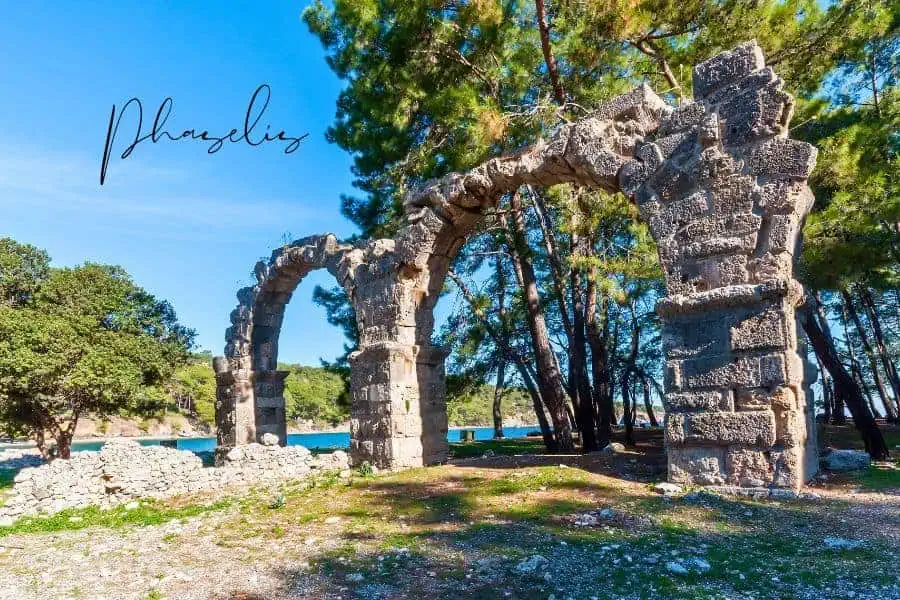 stone arch ruins of phaselis surrounded by pine trees and a glimpse of the sea