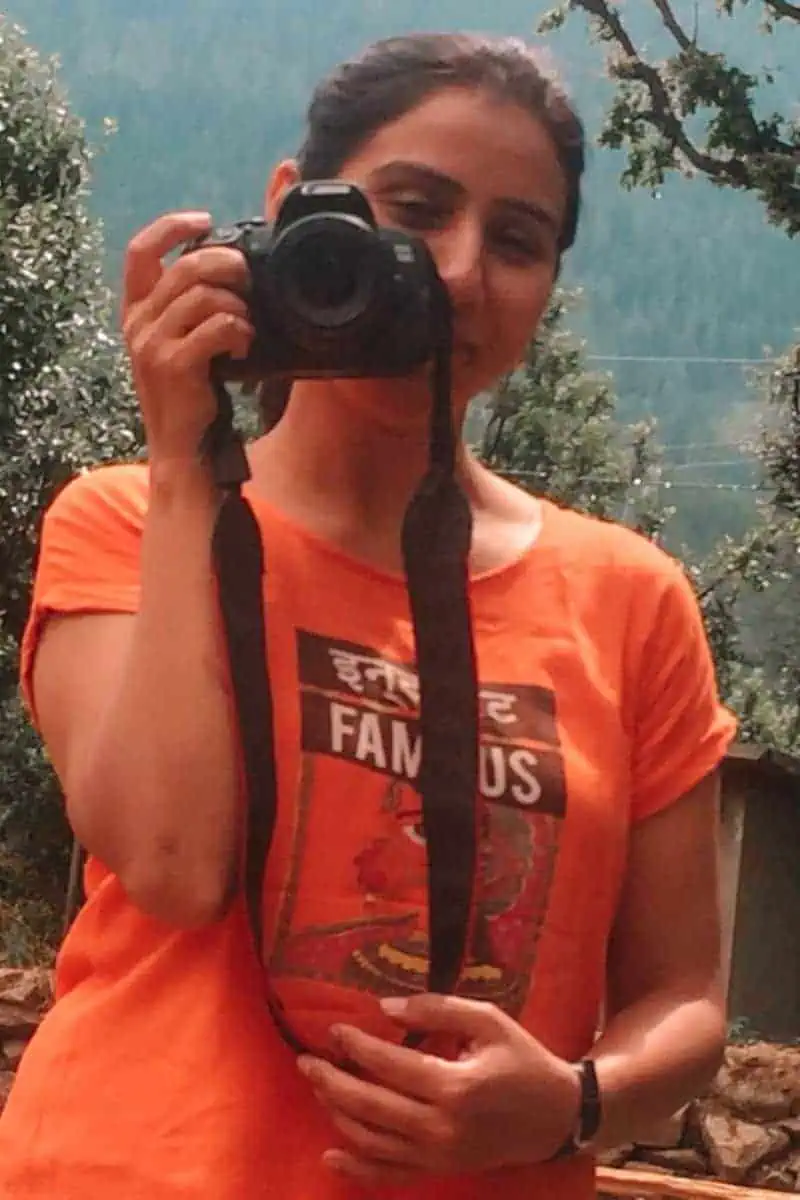 Faraway Notes writer posing with a camera in kheerganga in himachal pradesh