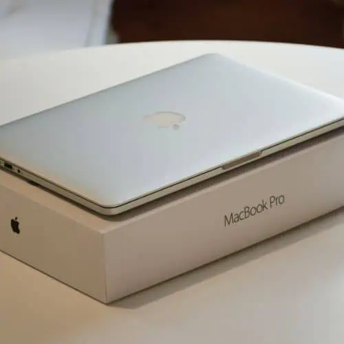 closed silver macbook pro placed on its white box on a white round table