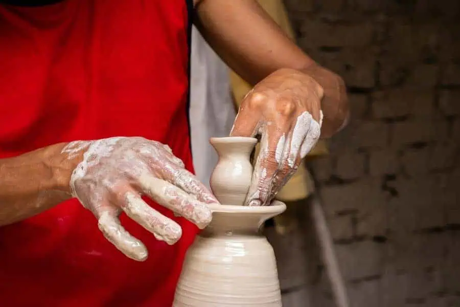 artisan making ceramic articles on the pottery wheel in a tradtional factory in raquira colombia