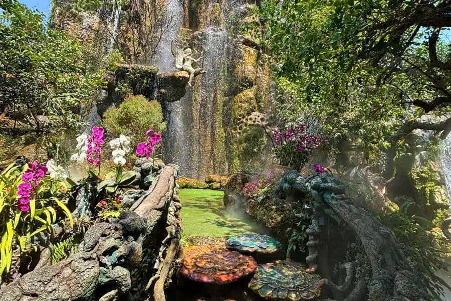 lush greens with a misty waterfall and pretty fairy statues and colorful steps at lalitta cafe in chiang rai