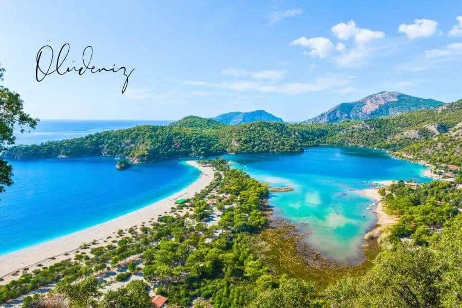 breathtaking view of the blue lagoon in ölüdeniz, one of the most beautiful places in turkey, surrounded by lush green hills and a long sandy beach stretching along the turquoise waters