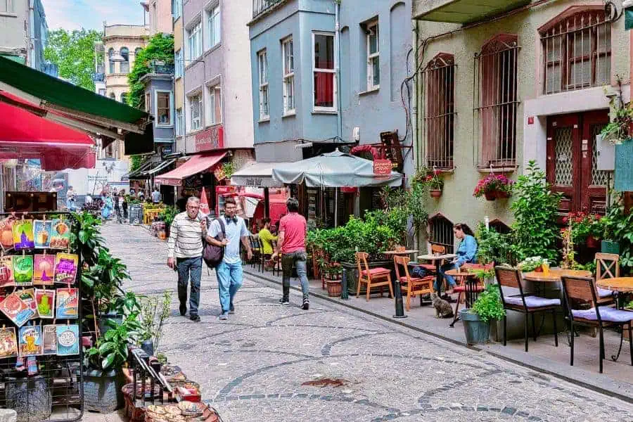 a charming street in istanbul's fatih district with cafes, plants, and people strolling