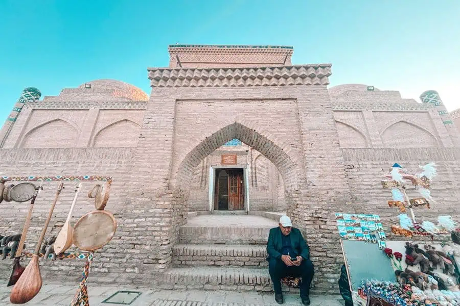 entrance of qozi kalon madrasa in itchan kala khiva with brick archway and handicraft stalls outside