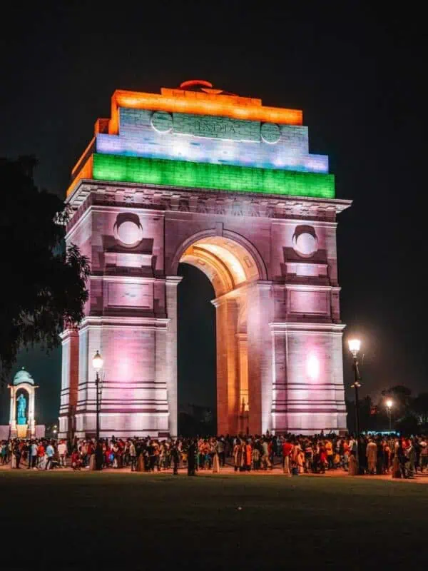 india gate lit up in tricolour at night, surrounded by people