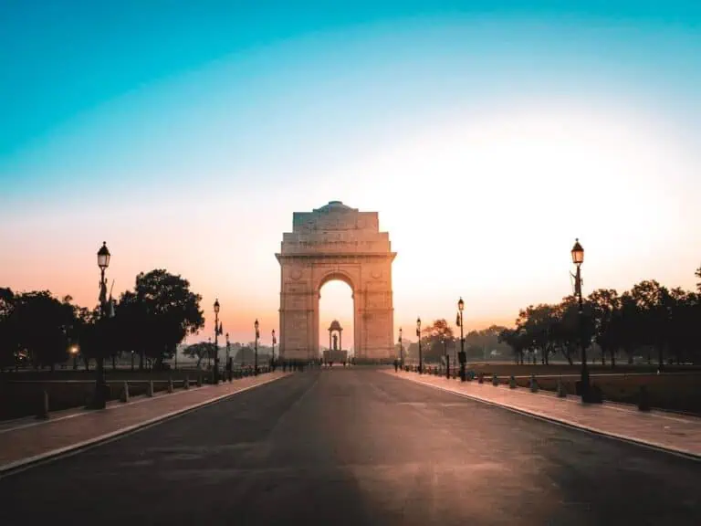 india gate glowing at sunrise, standing tall at the end of kartavya path in new delhi with warm morning light, empty road and soft gradient sky adding to the serene early hour scene