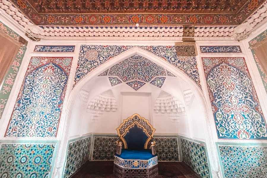 ornate royal room with colorful tiles and a blue throne inside khudoyar khan palace