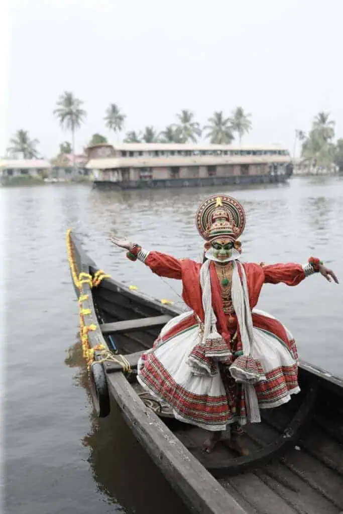 kathakali dancer in traditional costume and makeup posing on a decorated boat in kerala backwaters, India