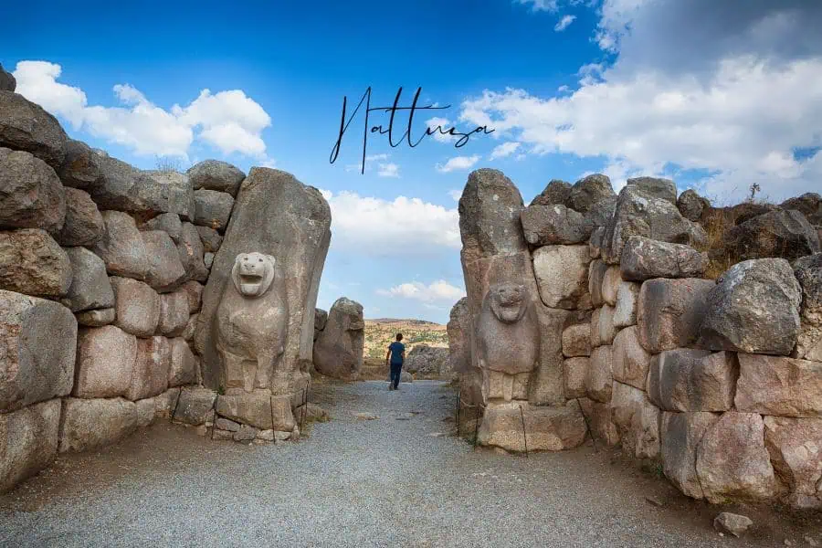  the lion gate of hattusa with massive stone sculptures and a person walking through