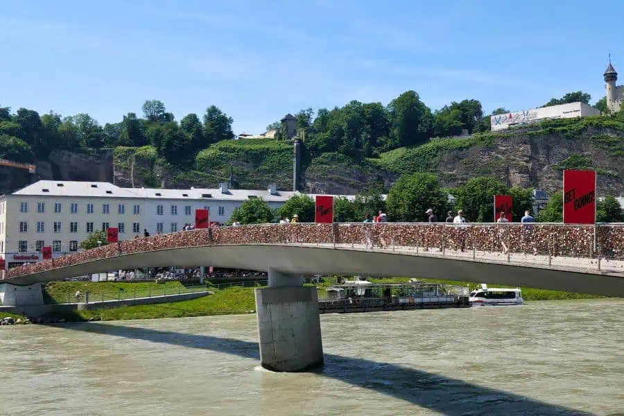 people crossing salzach river via makarsteg footbridge aka marko-feingold-steg aka love lock bridge in salzburg