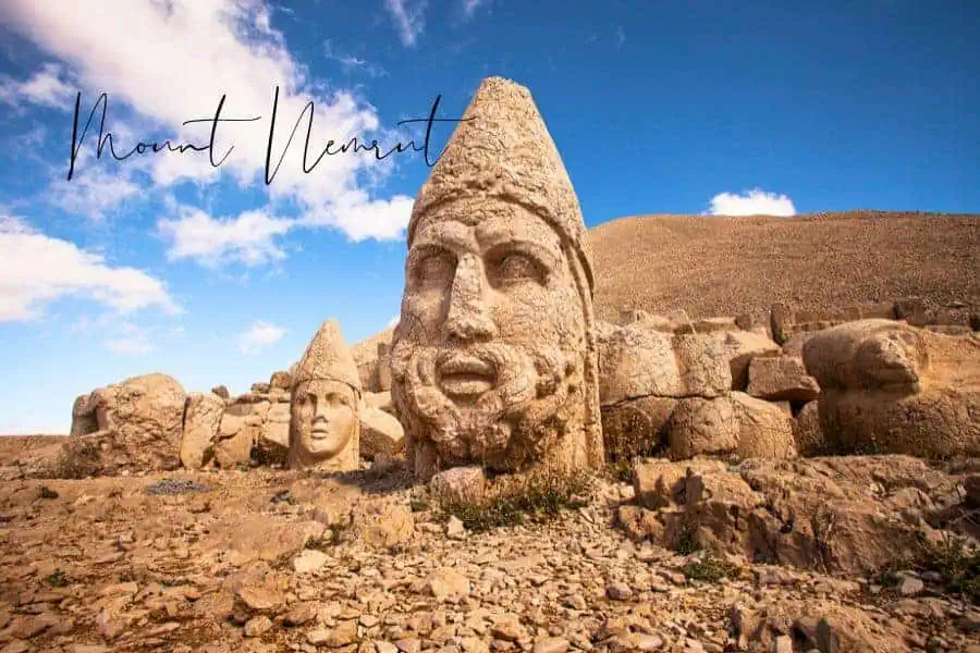 colossal stone heads scattered across a rugged mountaintop, standing against a dramatic sky