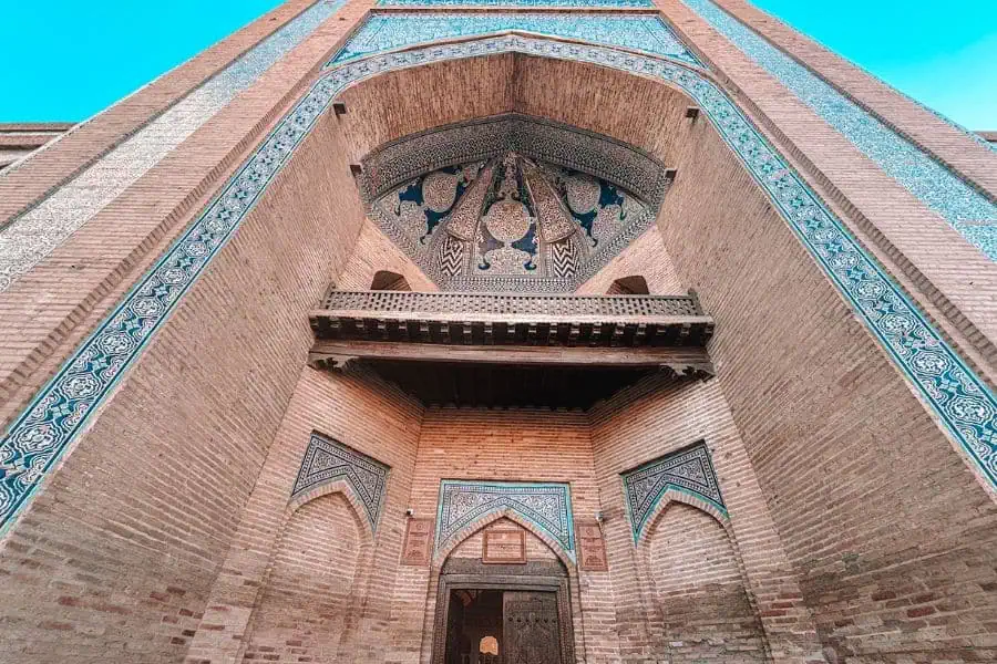 entrance of muhammad amin khan madrasa in itchan kala khiva with blue tilework and carved wooden balcony