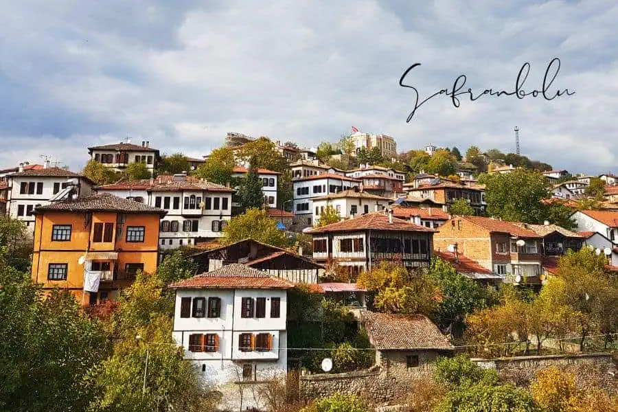 scenic hillside view of safranbolu’s well-preserved ottoman houses, with red-tiled roofs and white facades, nestled among green trees
