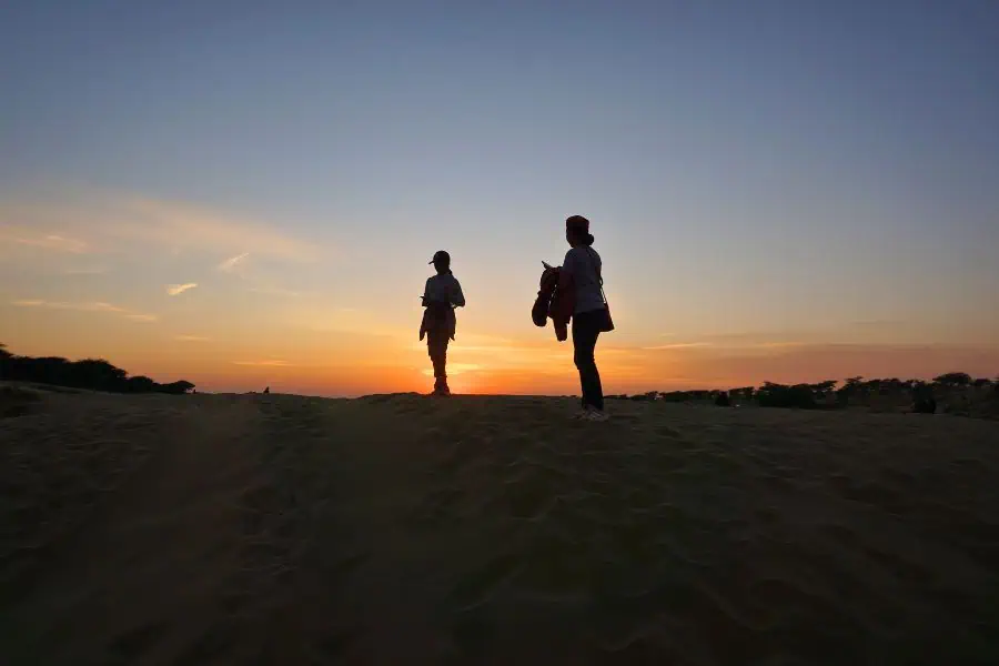 our silhouettes while walking through the sand dunes during sunset at thar desert jaisalmer