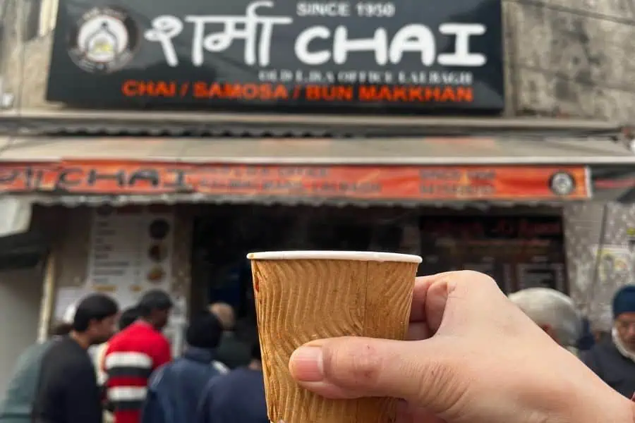 paper cup of hot chai held outside sharma chai stall in lucknow