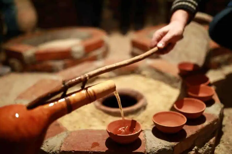 person pouring wine from qvevri using orshimo in kakheti georgia
