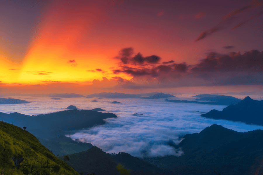 sunrise over phu chi fa forest park in chiang rai, thailand, with a sea of clouds covering the valleys and vibrant orange and purple hues in the sky