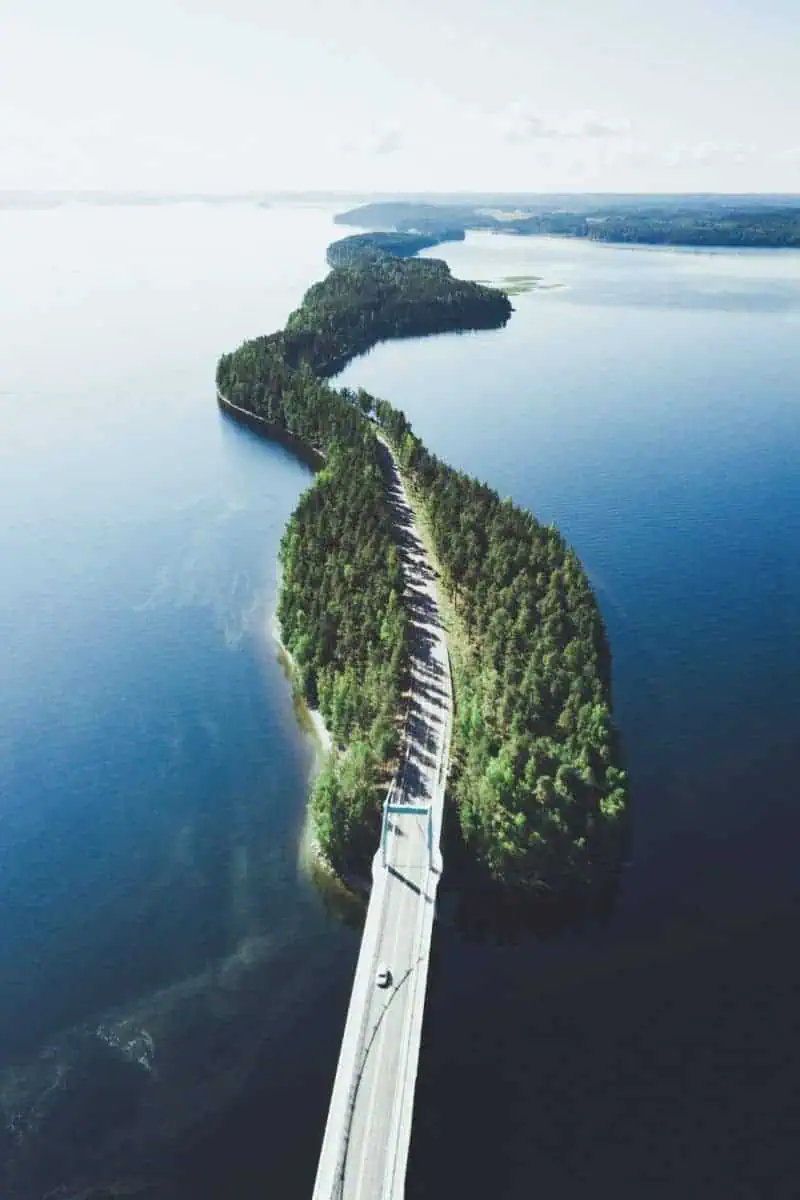 aerial view of the scenic Pulkkilantie road in Asikkala, Finland, winding through narrow forested islands surrounded by the serene blue waters of the Finnish Lakeland