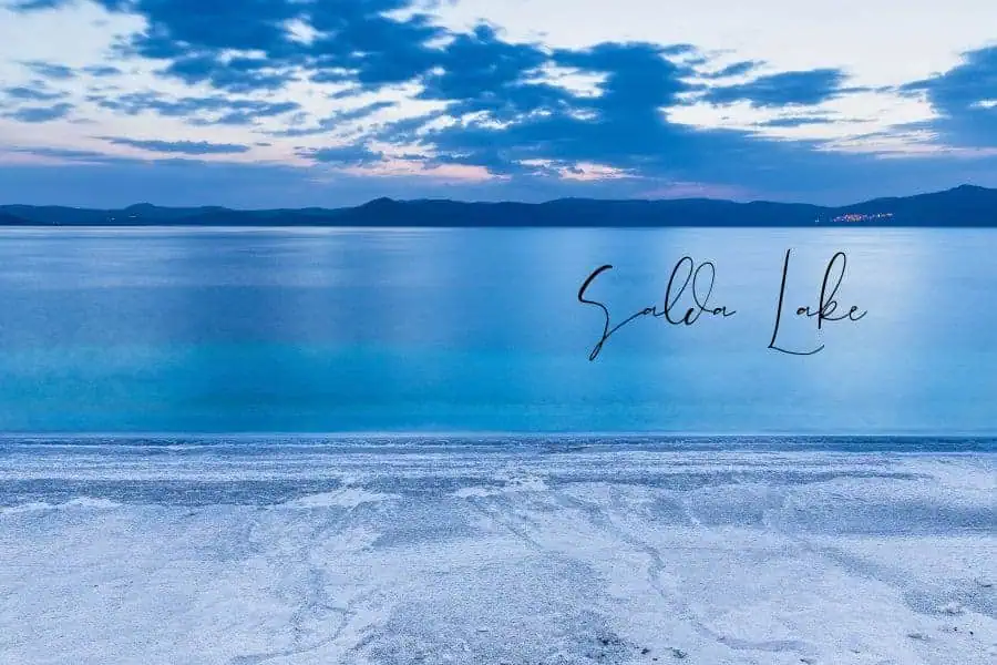 a serene view of salda lake with crystal-clear turquoise water and a white sandy shore at sunset
