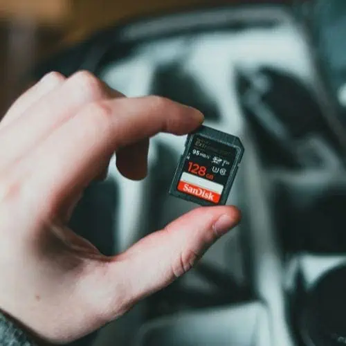 a girl holding a 128gb sandisk extreme pro memory card