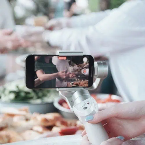 smartphone mounted on a handheld gimbal filming a food scene at a gathering
