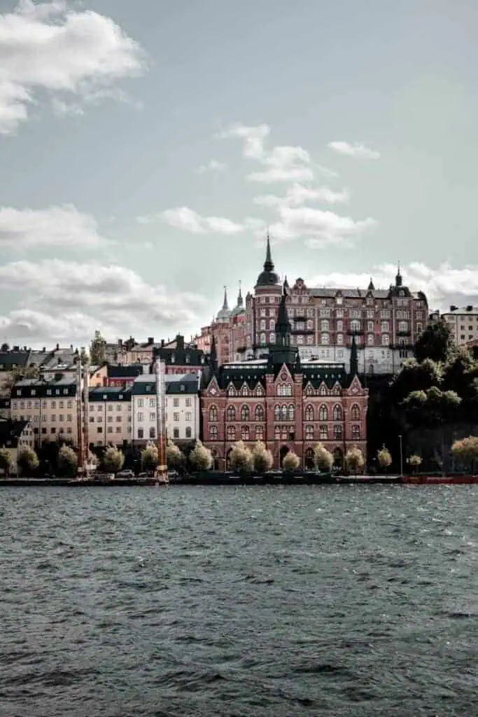 waterfront buildings and historic architecture of stockholm, sweden with sailboats and cloudy sky