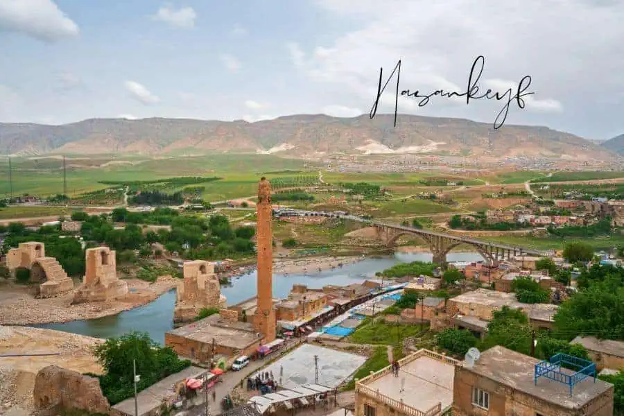 he historic town of hasankeyf, turkey, with ancient ruins, a tall minaret, and a bridge over the tigris river