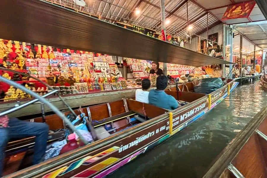 tourists in boats shopping at stalls at damnoen saduak floating market near bangkok