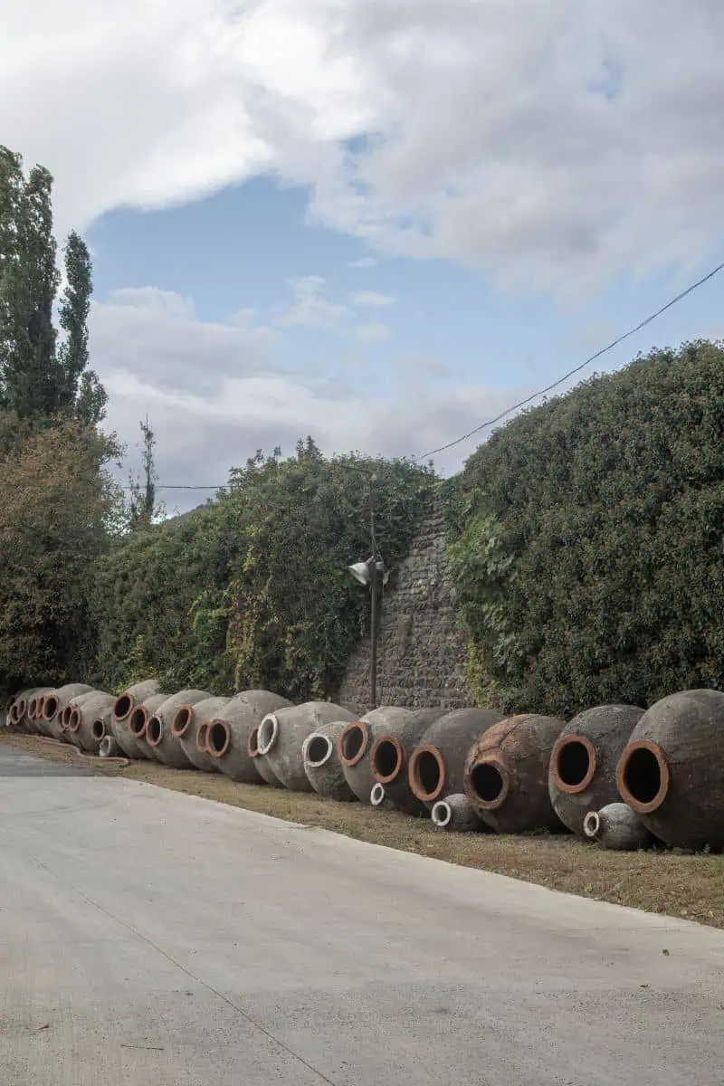 traditional georgian qvevri clay wine pots resting along a stone wall in kakheti
