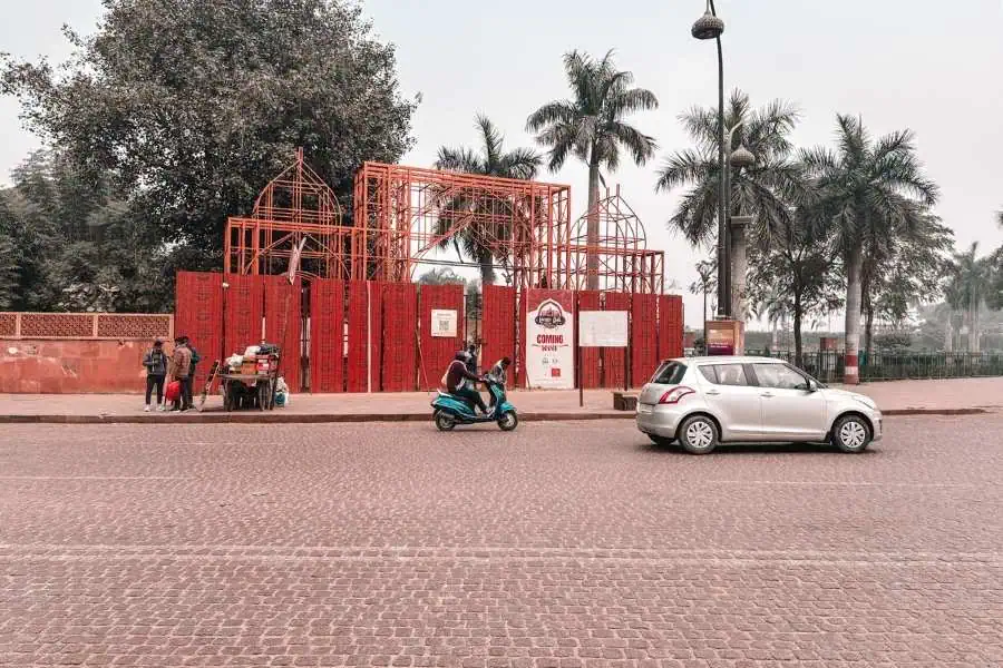 lazeez gali entrance under construction with red barricades and palm trees, lucknow