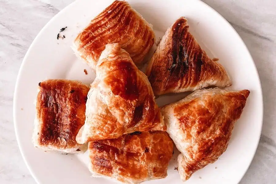 freshly baked uzbek samsa pastries with golden flaky layers served on a white plate