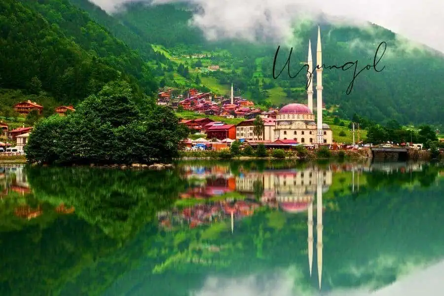 a picturesque view of uzungöl, turkey, with a mosque and traditional houses reflecting on the calm waters of the lake