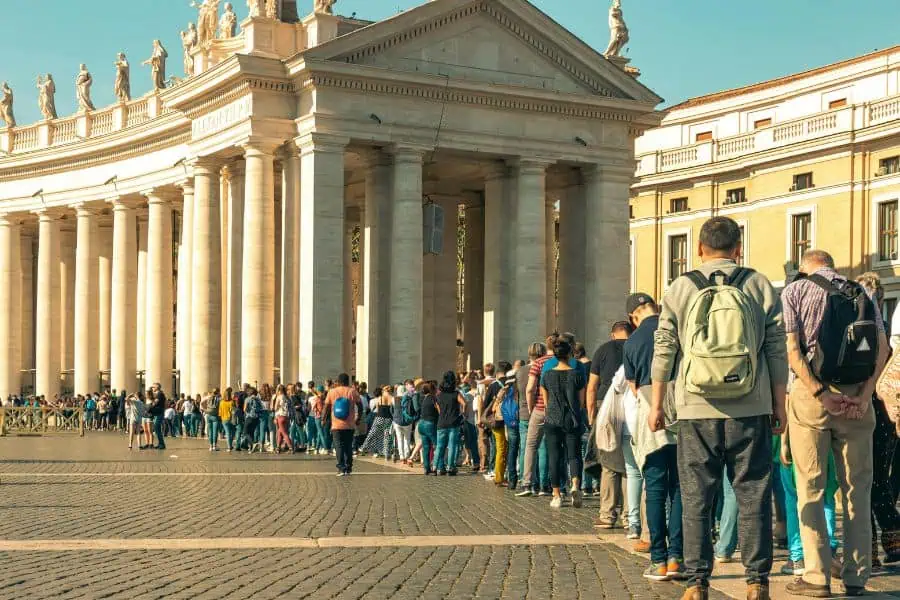 Long queue of visitors waiting in line outside a European landmark, showing orderly queue culture