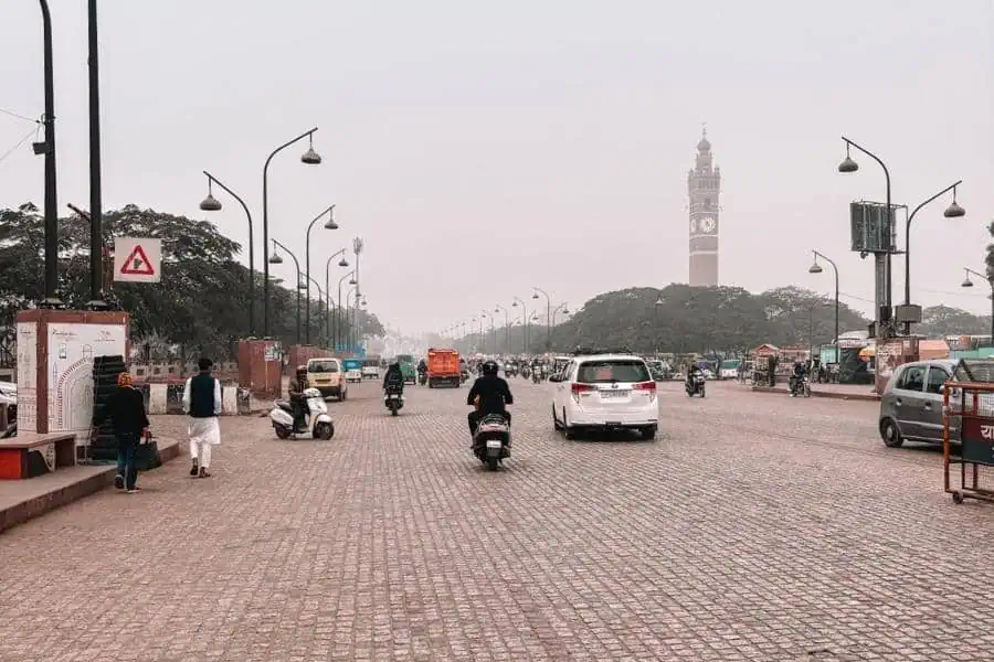 wide hussainabad road with traffic and clock tower in the distance, lucknow